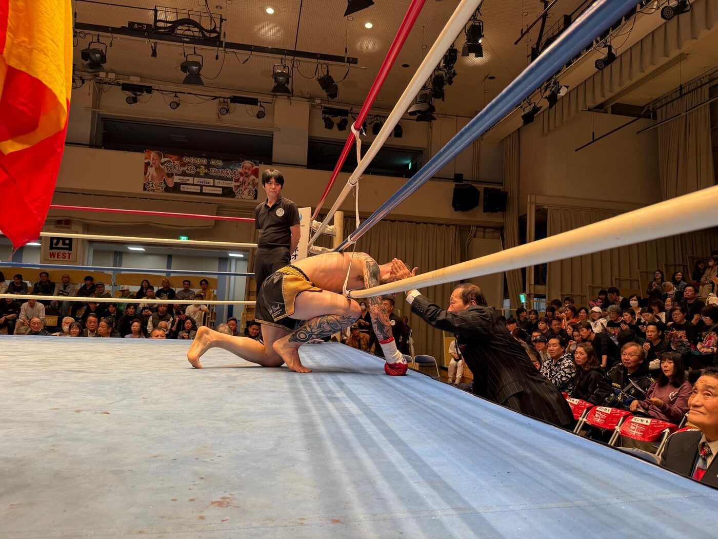 Ihara Kaicho reaches out to a fighter kneeling at the ropes after the bout, Japan